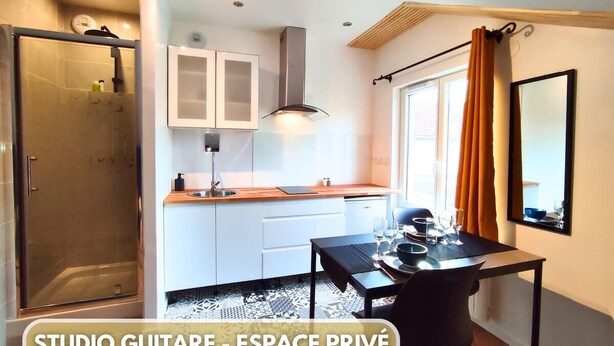 A modern kitchen with white cabinets, a dining table, and a shower area.