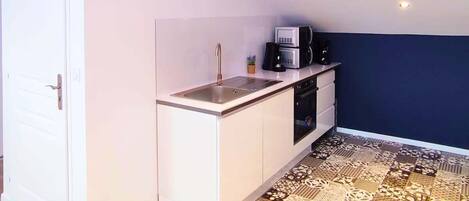 Een kleine keuken met een spoelbak, magnetron en oven.