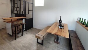 Une cuisine compacte avec un comptoir-bar en bois, des tabourets et une table à manger ornée de bouteilles.