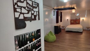 Une chambre moderne avec un plancher en bois, un lit, un fauteuil en forme de haricot vert et un porte-bouteilles fixé au mur.