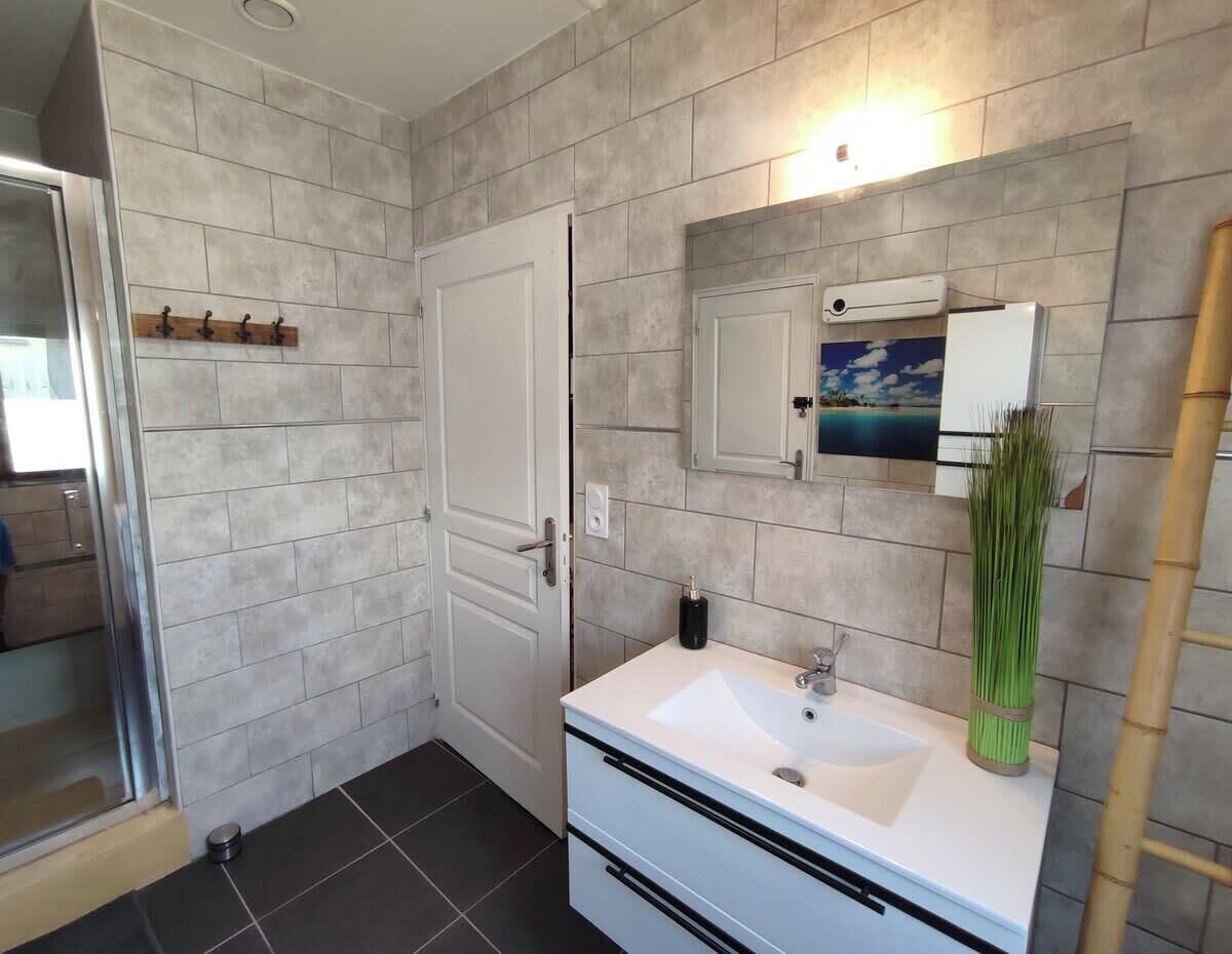 A bathroom with a white sink, a mirror, a towel rack, and a shower area.