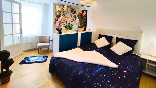 Ein Schlafzimmer mit einem Bett, einem Sessel, einem Schminktisch und einem Fenster.