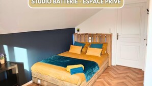 Een studio slaapkamer met een bed, een houten hoofdbord en een visgraat vloer.