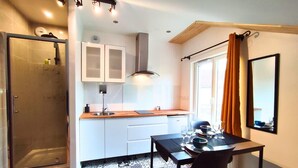 Een modern studio-appartement met een kitchenette, een eethoek en een douche.