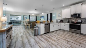 A modern kitchen with white cabinets, a stainless steel dishwasher, and a granite countertop. - 9BR Villa Home Theater Pool Sleeps 16 (Davenport)