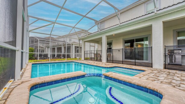 A swimming pool with a glass ceiling, surrounded by a patio area with outdoor furniture. - 9BR Villa Home Theater Pool Sleeps 16 (Davenport)