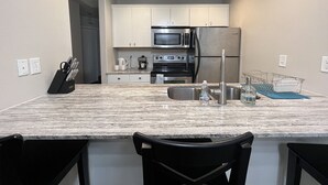 A modern kitchen with white cabinets, stainless steel appliances, a marble countertop, and a built-in sink. - PARIS - 2 beds / Free garage parking / Downtown Salt Lake City (Salt Lake City)