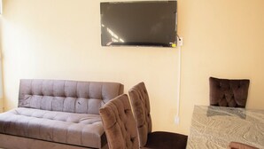 Una sala de estar con un sofá, dos sillones, una mesa de centro y un televisor de pantalla plana montado en la pared.