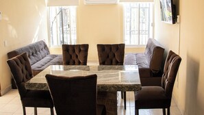 Comedor con una mesa de mármol y seis sillas tapizadas en tono marrón.