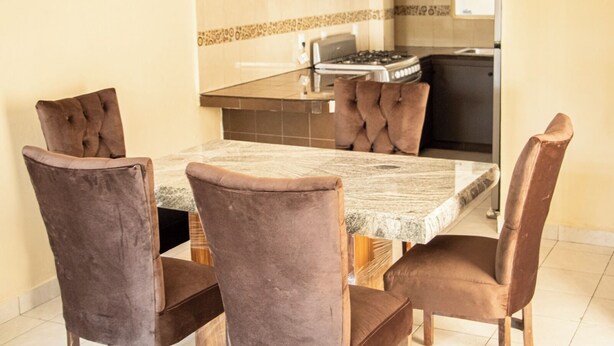 Un comedor con una mesa rectangular y seis sillas tapizadas en tono café.
