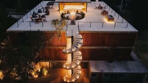 Una casa moderna con escalera en espiral, una terraza en la azotea con mobiliario y una chimenea central.