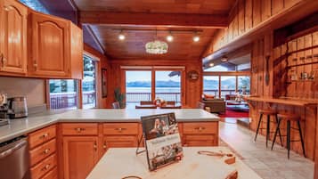 A wooden kitchen with a large island, wooden cabinets, and a view of mountains through the windows.