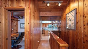 A wooden interior with a bar area, a dining space, and a kitchen. - Paradise cove - A Mid-Century Modern Waterfront Retreat (Ketchikan)