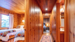 A wooden cabin interior with two beds, a hallway, and a bathroom. - Paradise cove - A Mid-Century Modern Waterfront Retreat (Ketchikan)