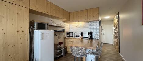 Een koelkast, een microgolfoven, kookgerei, borden en bestek