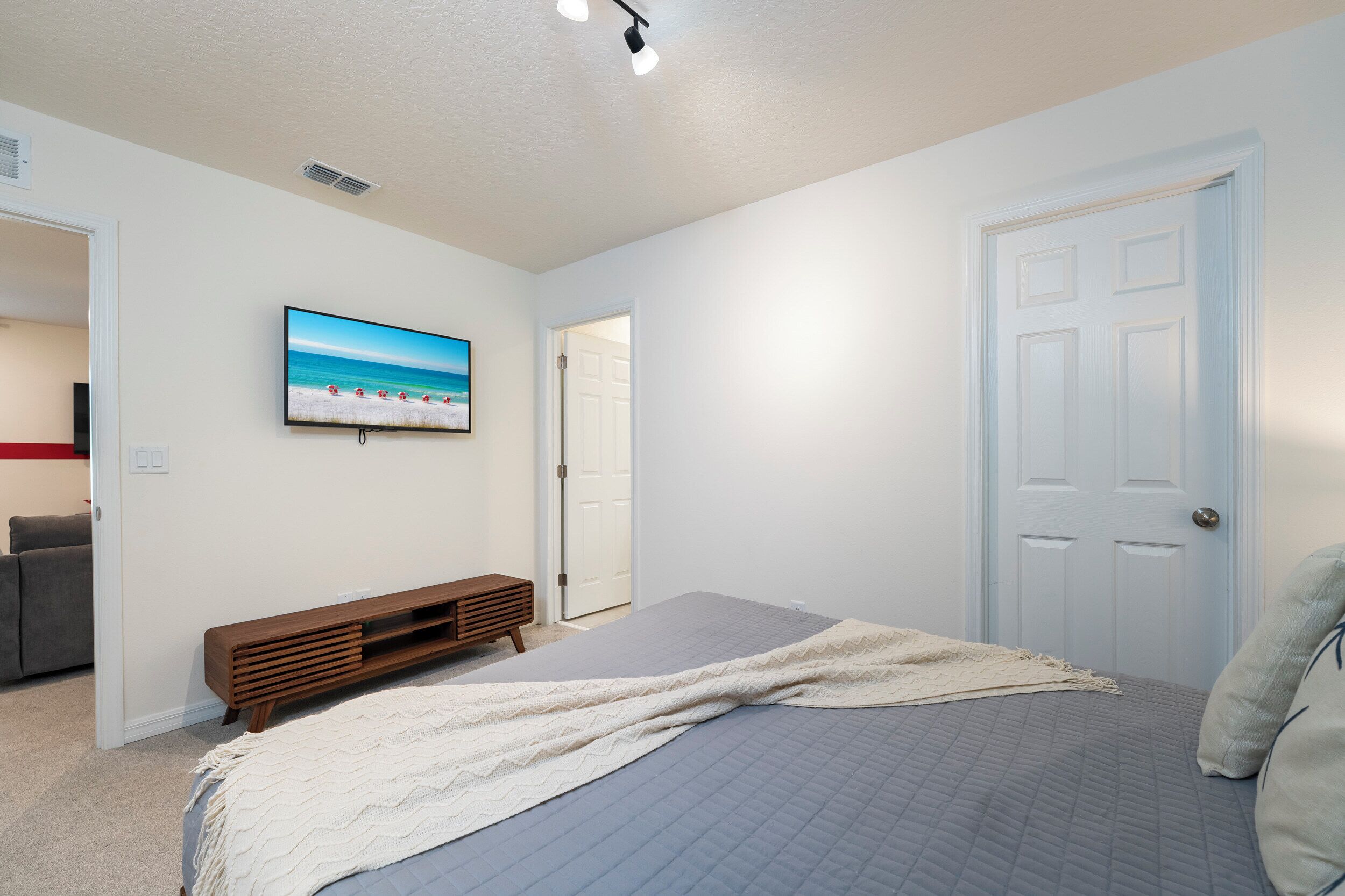 Une chambre à coucher avec un lit, une télévision, une porte et un banc.