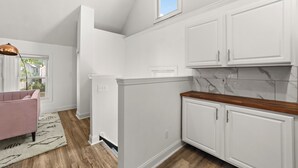 A modern kitchen with white cabinetry, a wooden countertop, and a view of the outdoors. - Cozy Loft Apartment in Ohio City (Cleveland)