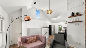 A modern kitchen with white cabinets, a refrigerator, and a dining area with a table and chairs. - Cozy Loft Apartment in Ohio City (Cleveland)