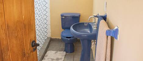 A small bathroom with a wooden door, a toilet, a sink, and a towel hanging on the wall.