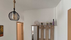 A hallway with a wooden door, a mirror, and a shelf with decorative items. - Seaside Escape – Calm, Safety, and Proximity (طنجة)
