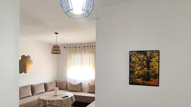 A living room with a sofa, a table, and a hanging light fixture. - Seaside Escape – Calm, Safety, and Proximity (طنجة)
