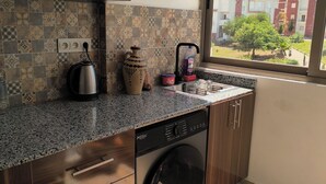 A kitchen with a washing machine, a kettle, and a water heater. - Seaside Escape – Calm, Safety, and Proximity (طنجة)