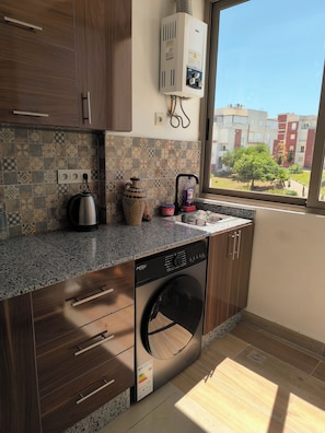 Una cocina equipada con lavadora, hervidor de agua y calentador.