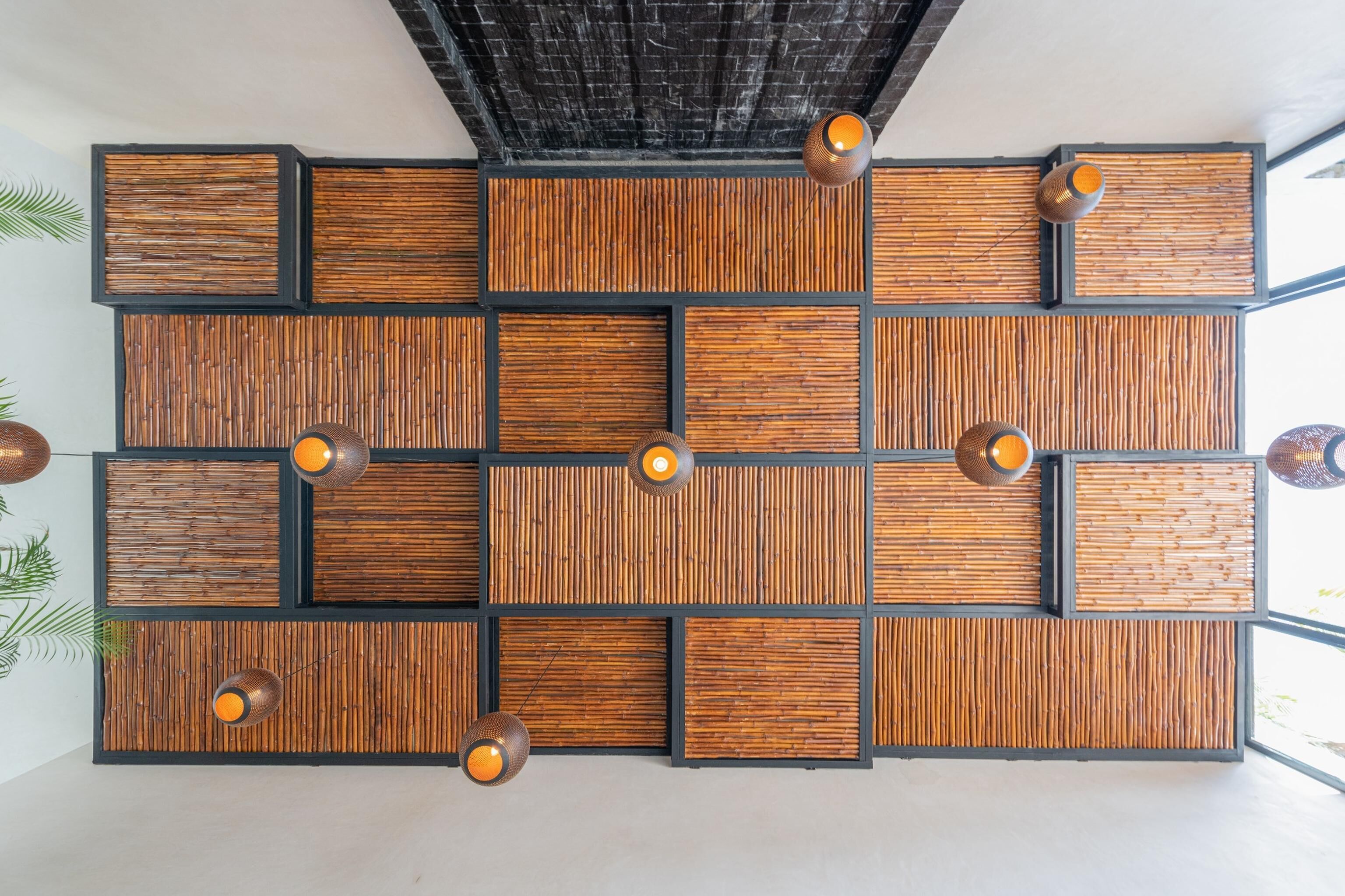 A modern wall with a geometric pattern of wooden panels and black frames, illuminated by pendant lights.
