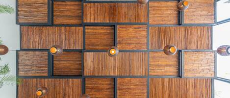 A modern wall with a geometric pattern of wooden panels and black frames, illuminated by pendant lights.