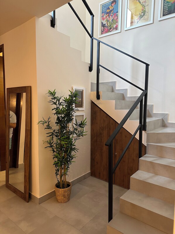 A staircase with a modern design, a potted plant, and framed artwork on the walls.