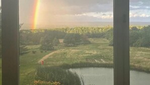 Une vue d’un paysage avec un arc-en-ciel, une étendue d’eau et un marqueur constitué d’un drapeau rouge.