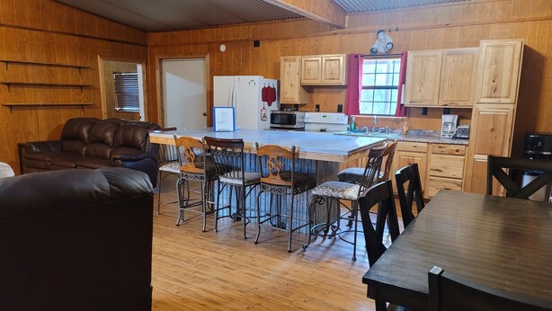 Una cocina acogedora con armarios de madera, una isla central con taburetes de bar y una mesa de comedor.