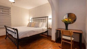 Un dormitorio con cama, escritorio, silla, espejo y ventilador de techo.