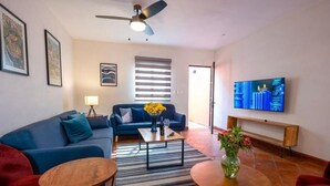 Una sala de estar moderna con un sofá azul, una mesa de centro y un televisor montado en la pared.