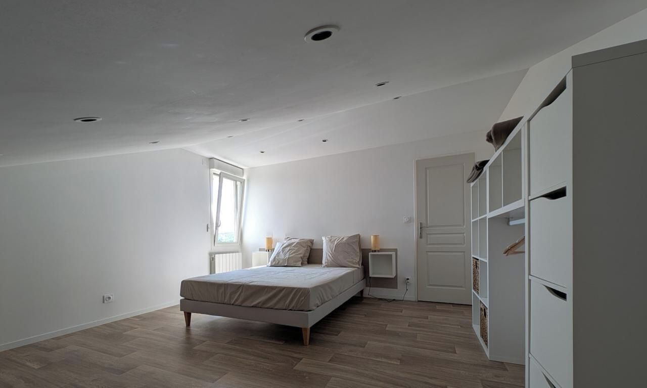 Ein Schlafzimmer mit einem Bett, Nachttischen, einem Kleiderschrank und einem Fenster.