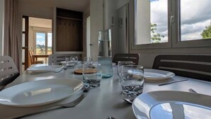 A dining table set for two with plates, cutlery, and glasses, a water bottle, and a glass pitcher. - Les Hautes Collières - ECHALAS (ECHALAS)