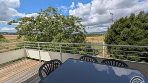 A balcony with a table and chairs, overlooking a rural landscape with trees and a power line tower. - Les Hautes Collières - ECHALAS (ECHALAS)