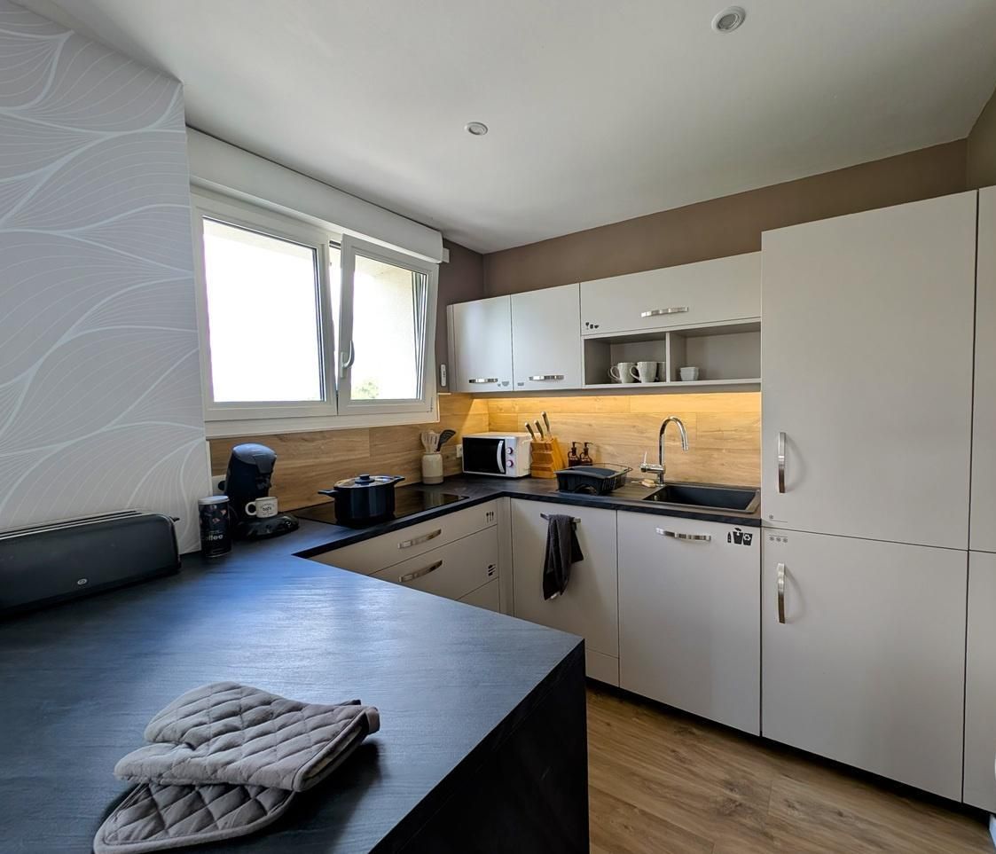A modern kitchen with white cabinets, a black countertop, and a window providing natural light.