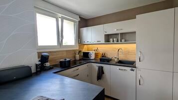 A modern kitchen with white cabinets, a black countertop, and a window providing natural light.