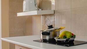 A kitchen with a stove, a pot, and a bowl of vegetables. - House Mary (Napoli)