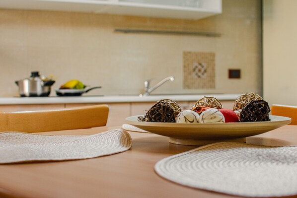 A dining table with a bowl of food, a chair, and a kitchen in the background.