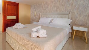 A neatly made bed with rolled towels, a wooden door, and a marble-patterned wall. - House Mary (Napoli)
