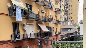 A multi-story residential building with balconies, air conditioning units, and a street with parked cars. - House Mary (Napoli)