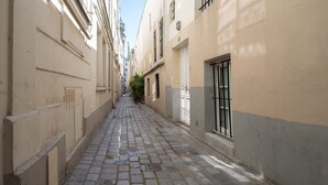 Une ruelle pavée bordée d’immeubles dotés de grandes fenêtres et de grandes portes.
