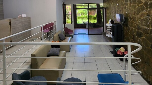 A modern waiting area with a stone wall, a reception desk, and a seating area with chairs and sofas. - Urban Backpack. Nómadas Digitales, Coworking wifi free 7/24. Rest and Chill (San Salvador)