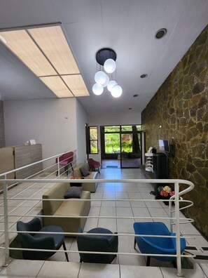 A modern waiting area with a stone wall, a reception desk, and a seating area with chairs and sofas.
