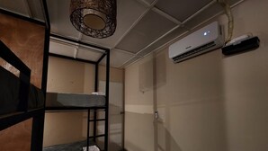 A small, compact room with bunk beds, a ceiling fan, and an air conditioning unit. - Urban Backpack. Nómadas Digitales, Coworking wifi free 7/24. Rest and Chill (San Salvador)