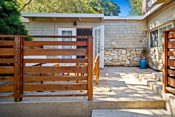 A wooden gate leading to a stone-walled building with a door and steps. - Carmel Cozy Cottage | Room for 4 (Carmel)