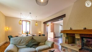 Ein Wohnzimmer mit einer Couch, einem Kamin und einem Essbereich im Hintergrund.