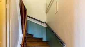 Eine Holztreppe mit Handlauf, die zu einem Zwischenpodest mit einer Tür führt.